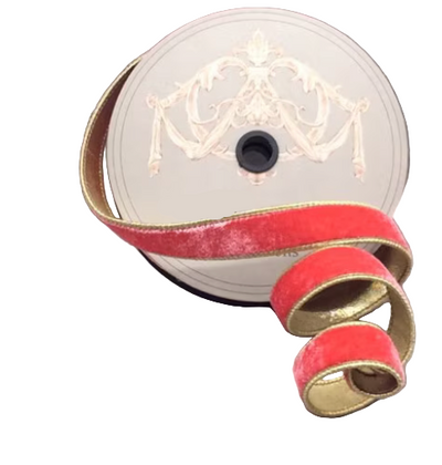 Spool of coral ribbon with gold edge on a gray surface
